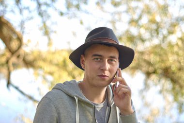 Sonbahar parkında şapka takan genç adam