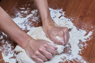 Kadın eller şef yakın çekim, hamur yoğurun, bir masada hamur pişirin