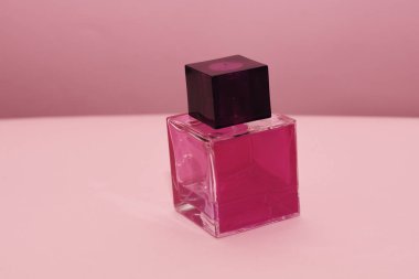 Pembe arka planda bir şişe parfüm.