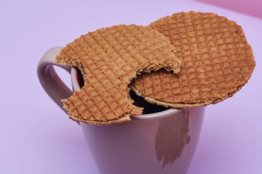 pembe arka plan üzerinde servis sıcak kahve veya çay fincan üstüne yerleştirilen waffle