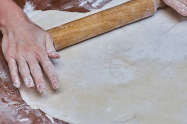 Ahşap masanın üzerinde pizza için el haddeleme hamur, yakın çekim. Pizza için hamur.