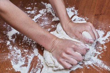 Kadın eller şef yakın çekim, hamur yoğurun, bir masada hamur pişirin
