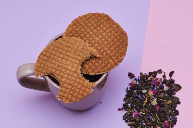 Stroopwafel sıcak kahve veya çay fincan üstüne yerleştirilen pembe arka plan üzerinde servis