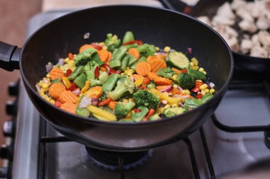 Kızartma tavasında lezzetli karışık donmuş sebzeler pişiriyorum.