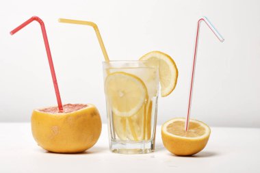 Turunçgiller beyaz arka planda dilimler ve pipet içerler 