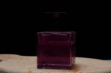 Koyu arka plan üzerinde ahşap tahta üzerinde Parfüm şişesi