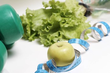 Mavi şeritli elma ve beyaz zemin üzerinde dambıl, diyet konsepti.