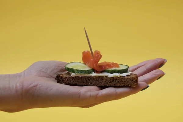 Mujer Sosteniendo Sándwich Salmón Mano Sobre Fondo Amarillo — Foto de Stock