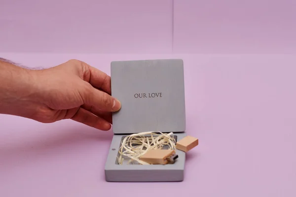 cropped shot of person opening box with our love inscription and flash drive