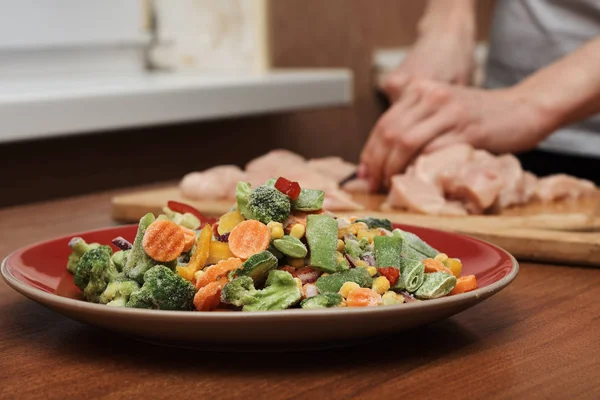 Mixed Frozen Vegetables Red Plate Woman Cut Meat Blurred Background — Stock Photo, Image