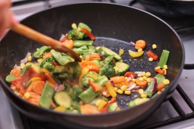 Kadın donmuş sebze pişiriyor.