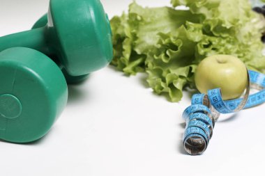 Mavi şeritli elma ve beyaz zemin üzerinde dambıl, diyet konsepti.