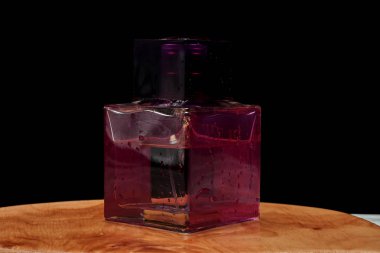 Koyu arka plan üzerinde ahşap tahta üzerinde Parfüm şişesi