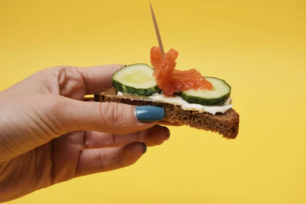 Mujer Sosteniendo Sándwich Salmón Mano Sobre Fondo Amarillo — Foto de Stock