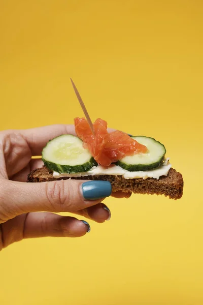 Mujer Sosteniendo Sándwich Salmón Mano Sobre Fondo Amarillo — Foto de Stock