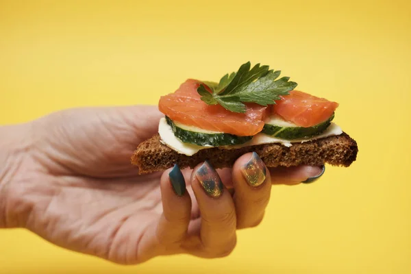 Mujer Sosteniendo Sándwich Salmón Mano Sobre Fondo Amarillo — Foto de Stock