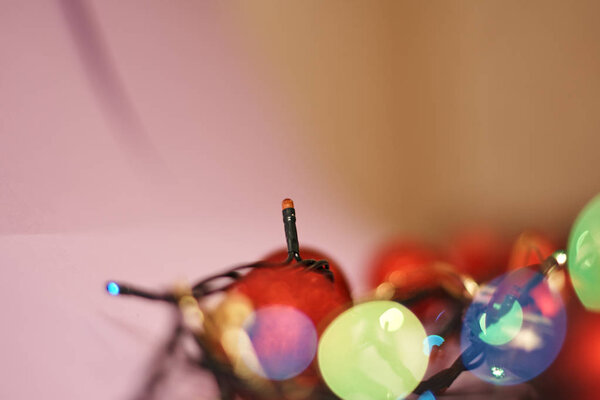 Red chirstmas balls with colorful lights of garland on pink background