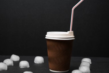 Siyah arka planda pipet içmek için buz ve kahvenin yakın plan görüntüsü  