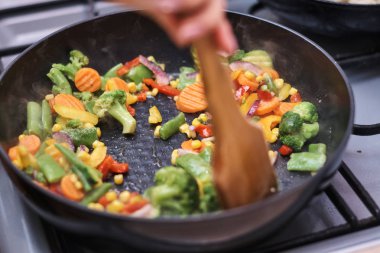 Kadın donmuş sebze pişiriyor.