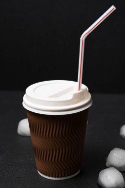 Siyah arka planda pipet içmek için buz ve kahvenin yakın plan görüntüsü  