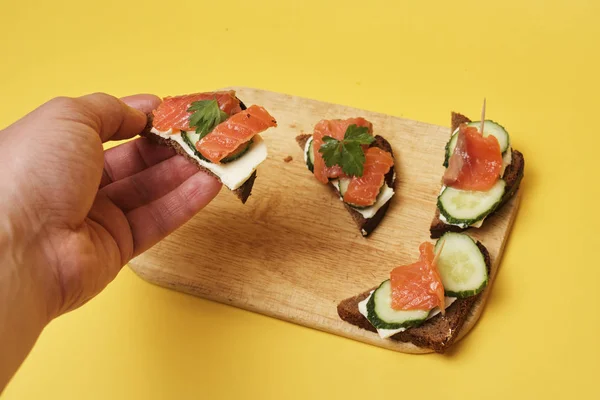 Sandwiches Con Salmón Pepinos Servidos Sobre Tabla Madera Persona Tomando — Foto de Stock