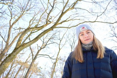 Sarışın kadın karlı kış parkında yürüyor.