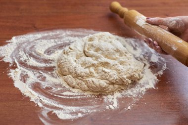 Ahşap bir tahtanın üzerinde hamur yoğuran kadının ellerini kapat.  