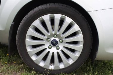 Bulutlu bir günde kırsal yolda park etmiş gümüş renkli parlak arabanın yakın plan görüntüsü.        