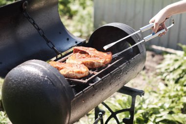 Kadın ızgarada et pişiriyor, barbekü yapıyor..