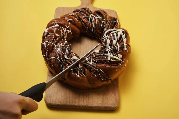 Woman cut fresh baked cake on wooden board with knife