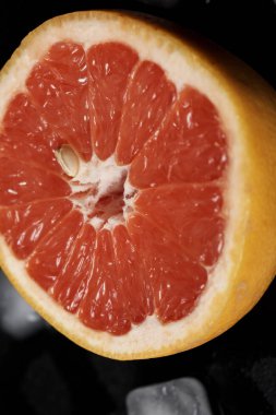 Siyah zemin üzerinde greyfurt dilimi ve buz küpleri     