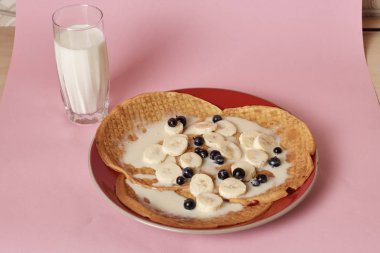 Siyah üzümlü krep ve bir bardak sütle servis edilen muz.