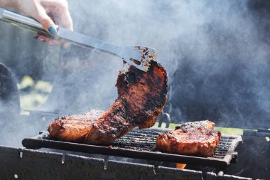 Kadın ızgarada et pişiriyor, barbekü yapıyor..