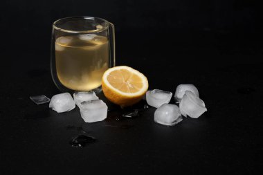 Limonlu bir bardak limonata ve koyu arkaplanda buz. 