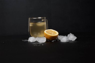 Limonlu bir bardak limonata ve koyu arkaplanda buz. 