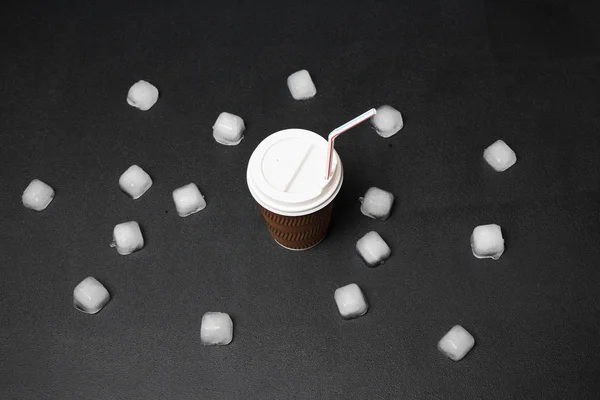 close-up view of ice cubes and coffee to go with straw on black background