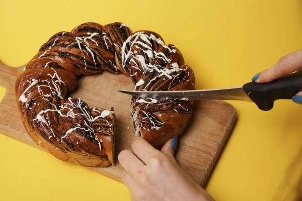 Woman cut fresh baked cake on wooden board with knife