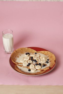 Siyah üzümlü krep ve bir bardak sütle servis edilen muz.