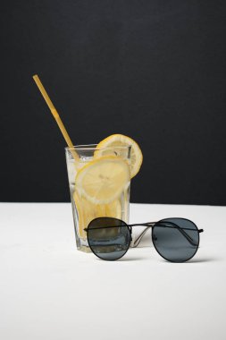 Masada limon dilimleri ve güneş gözlüğü olan taze yaz kokteyli, yakın görüş.
