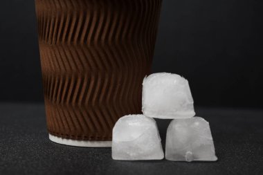 Siyah zemin üzerinde kağıt bardak ve buz küplerinin yakın plan görüntüsü