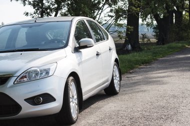 Güneşli bir günde kırsal yolda gümüş rengi parlak bir araba.