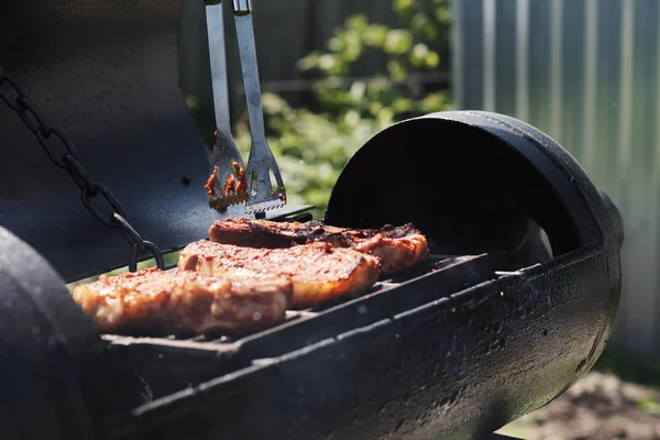 Woman grilling meat outdoors on grill, barbecue.