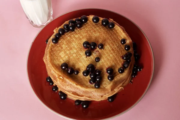 Stack of crepes with black currant served with glass of milk