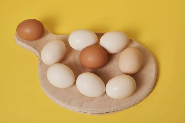 Telur Papan Kayu Dengan Latar Belakang Kuning Cerah — Stok Foto