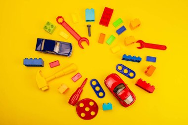 Renkli oyuncakların üst görünümü ve beyaz ve sarı arkaplan üzerine inşa araçları
