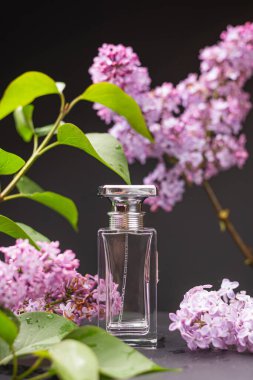 Parfüm şişesi ve çiçekler ahşap bir masada.