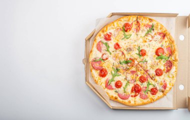 Beyaz arka planda domatesli, salamlı ve peynirli pizzanın üst görüntüsü.  