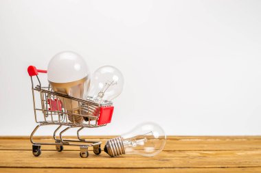 Beyaz arka planda ampuller ve alışveriş arabası