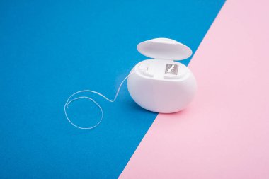 Mavi ve pembe arka planda diş ipinin yakın plan görüntüsü. Boşluğu kopyala.