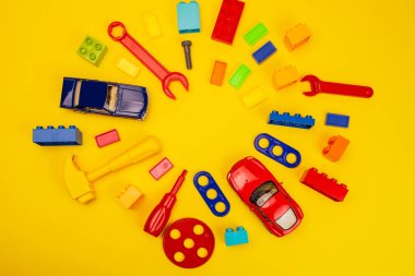 Renkli oyuncakların üst görünümü ve beyaz ve sarı arkaplan üzerine inşa araçları